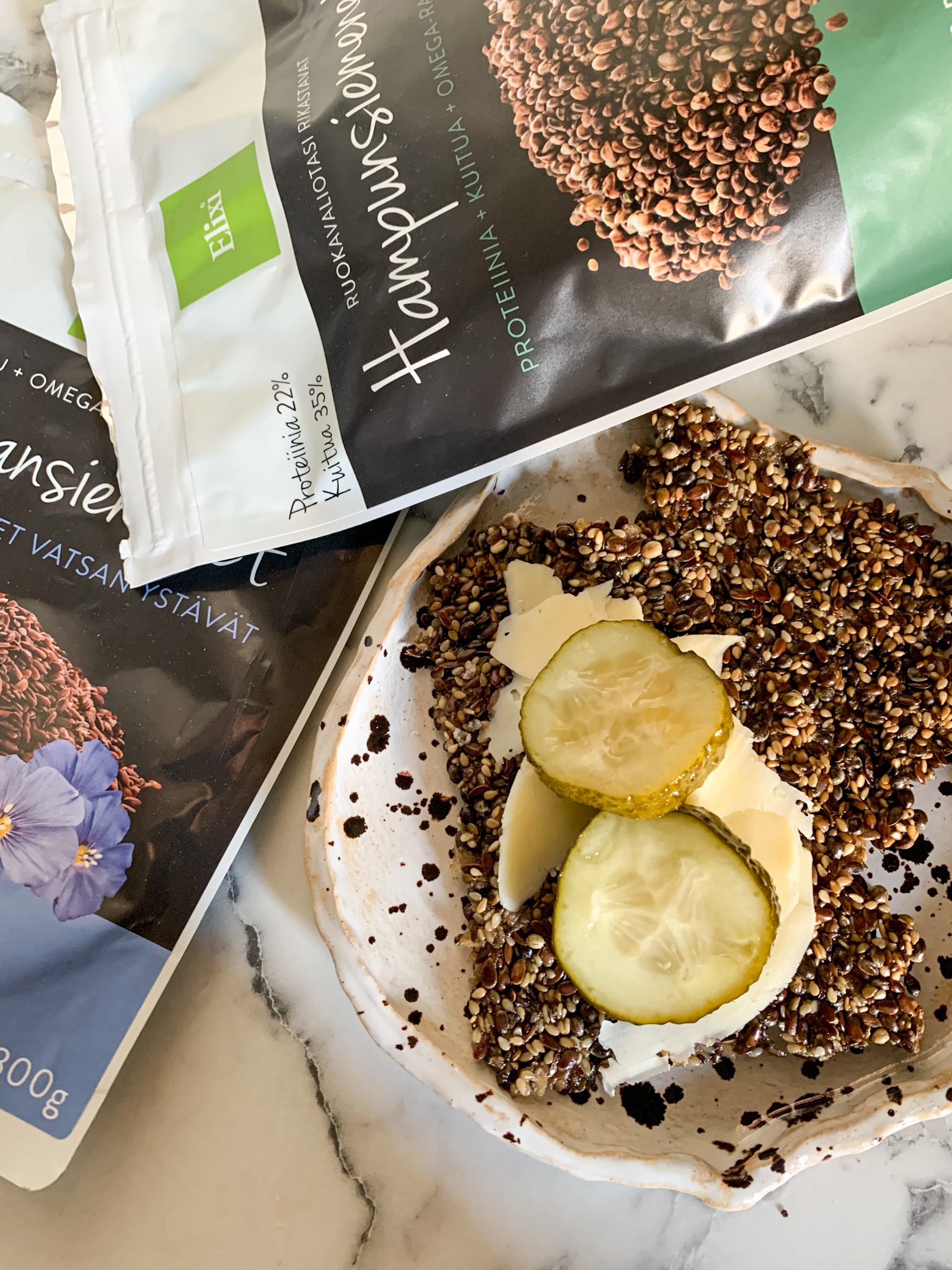 Siemennäkkileipä siemennäkkileipä valkoisella lautasella, jonka päällä juustoa ja suolakurkkua.
